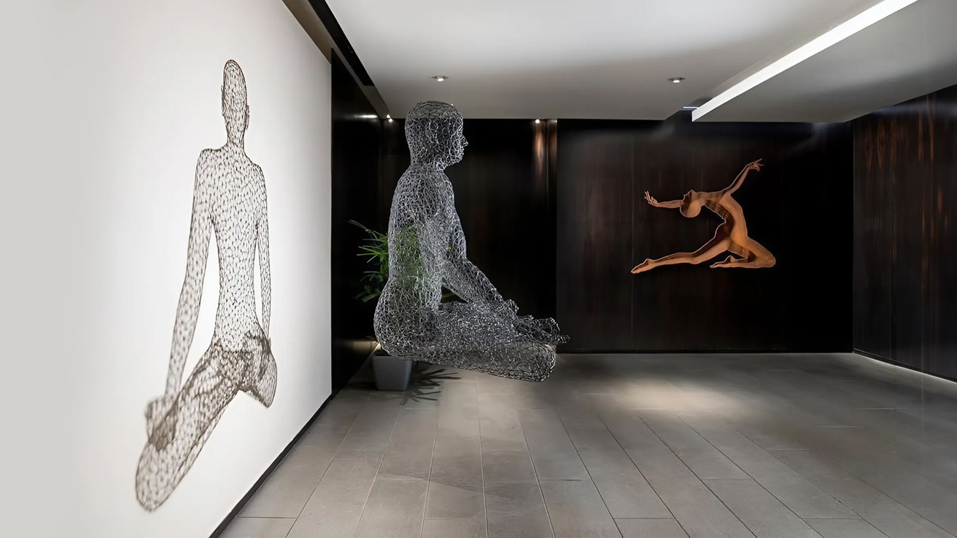 Floating wire-mesh figures and a bronze dancer in a corridor