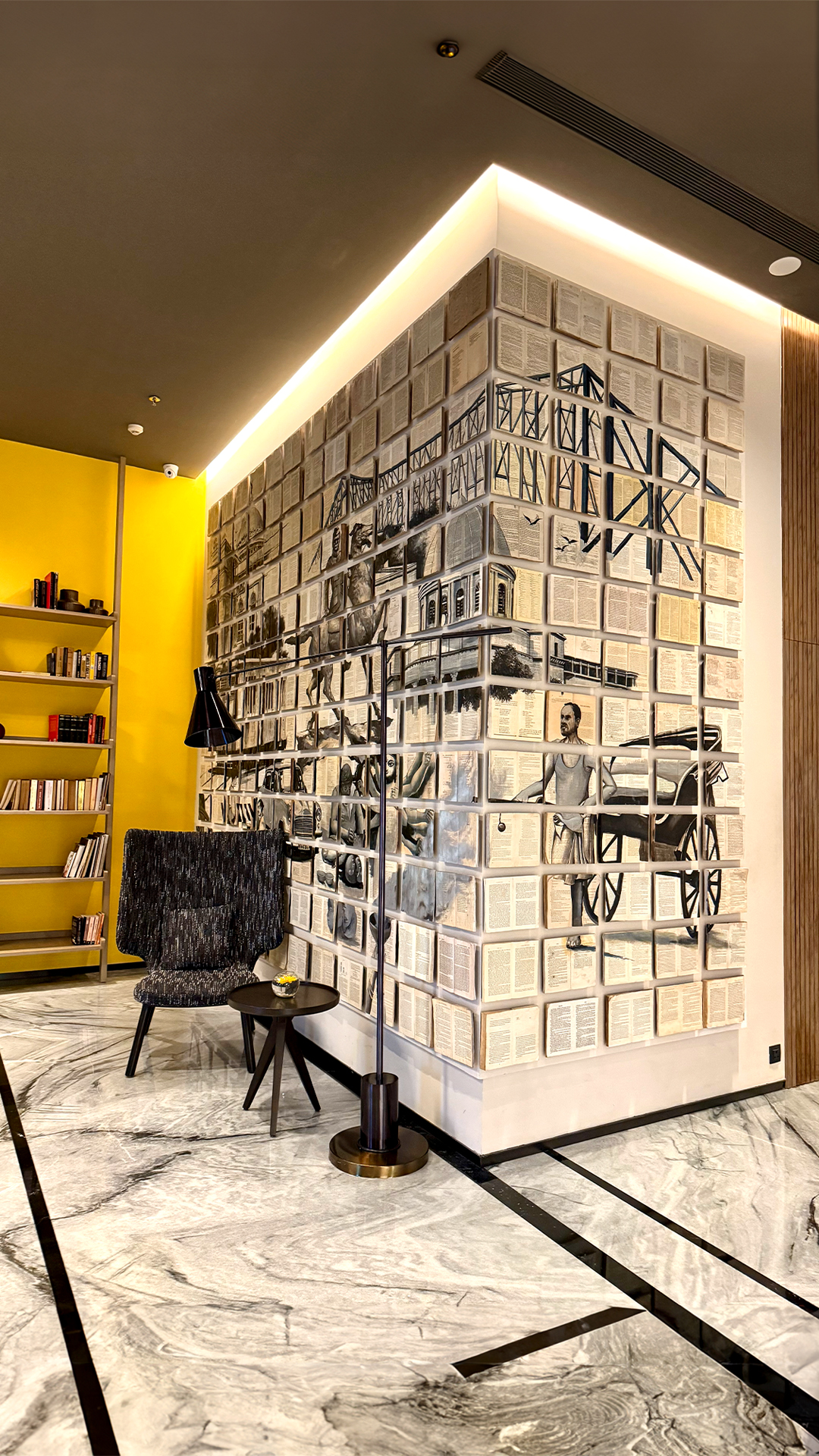 A book-page mural wall in a Kolkata lobby — The Artemist